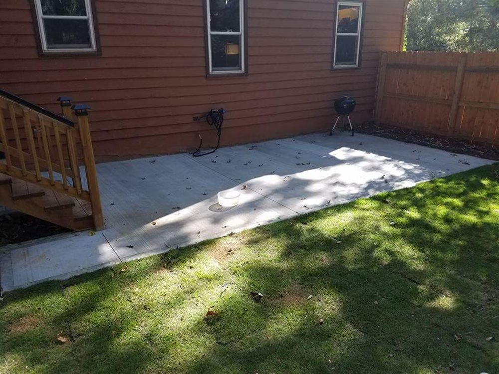 Poured concrete patio beside a lawn and privacy fence