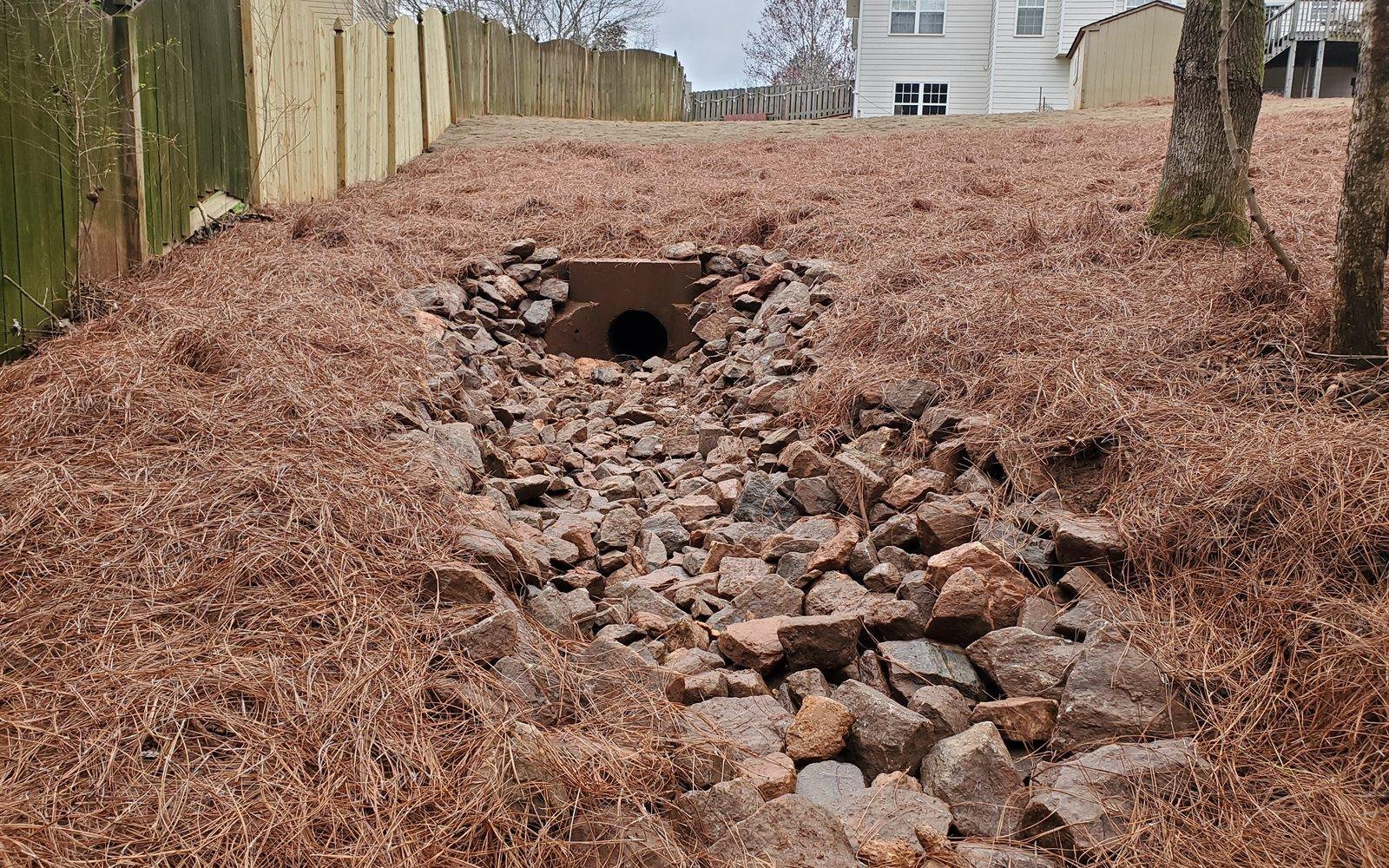 River-rock dry creek bed channeling drainage across a North Georgia yard