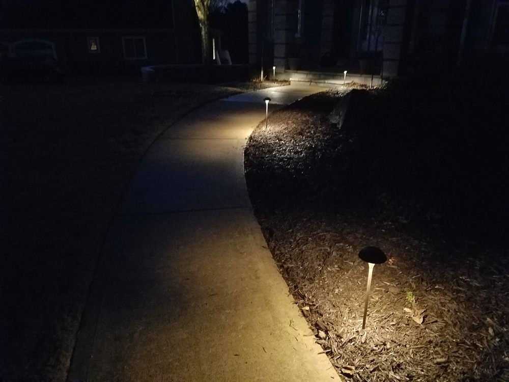 Low-voltage path light glowing along a curved driveway at night