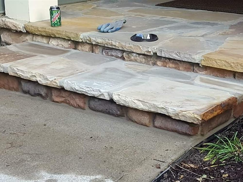 Wide flagstone slab steps with stone risers leading up to a patio