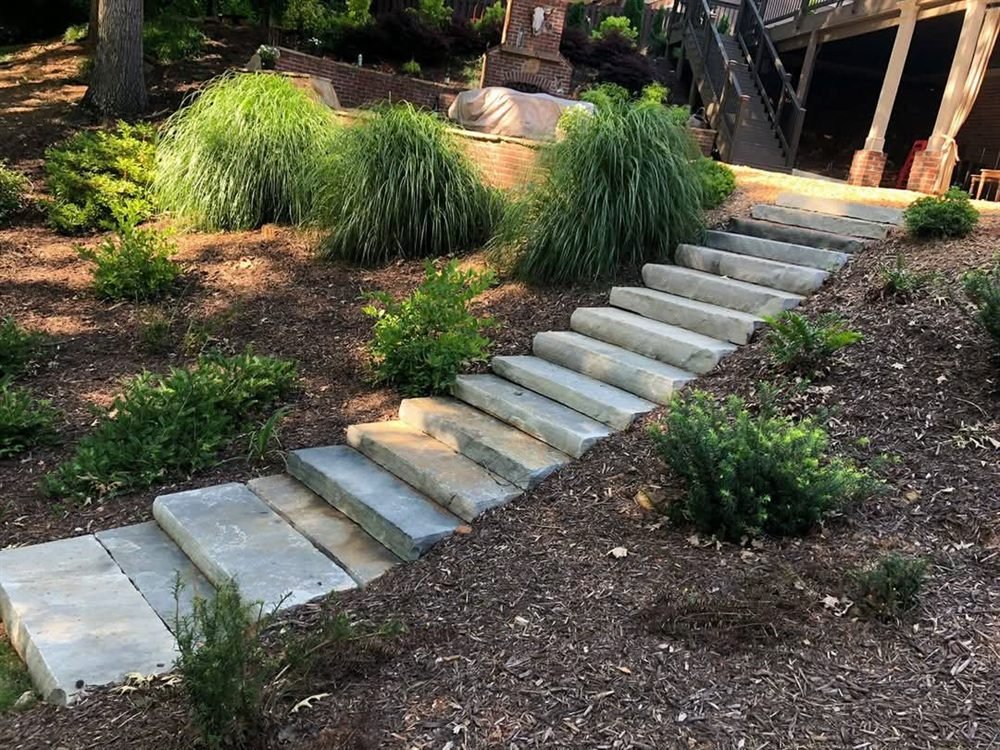 Limestone stair treads set into a planted hillside with ornamental grasses