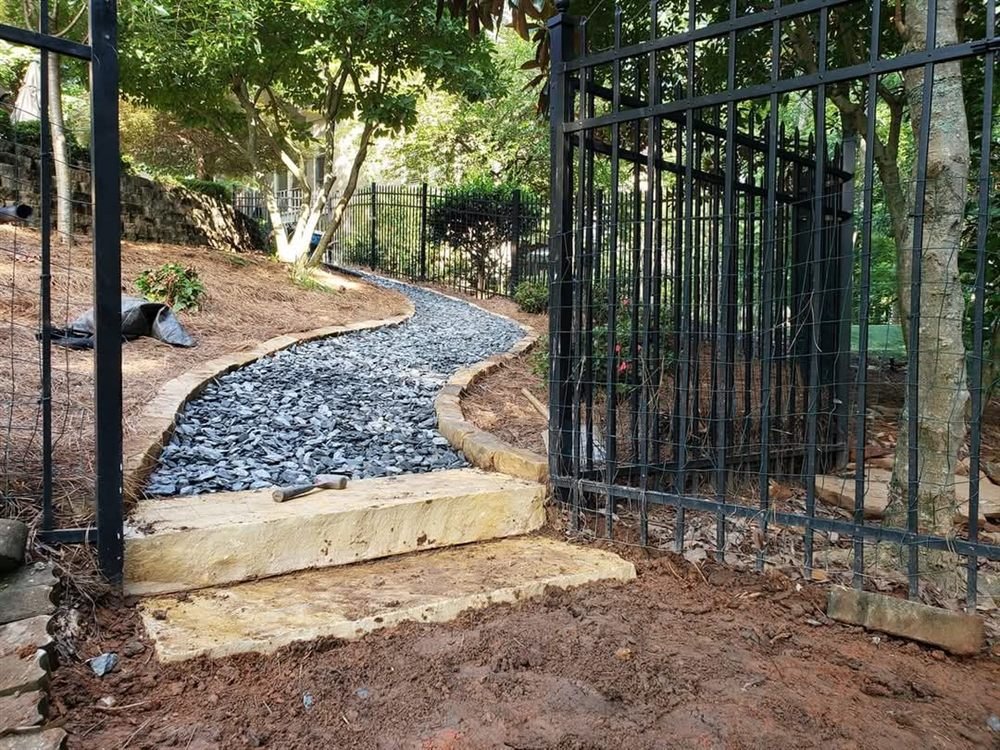 Slate-chip and cobble pathway leading through an iron gate